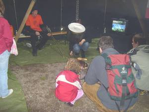 Gäste backen sich Stockbrot über Lagerfeuer in der Pfadfinderjurte